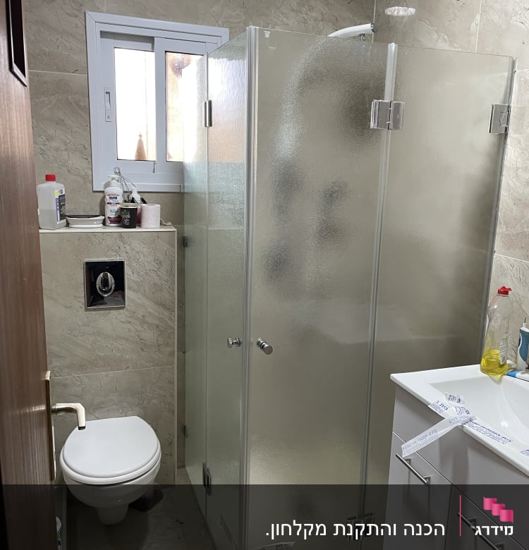 מקלחון זכוכית עם דלתות מתכת בחדר אמבטיה